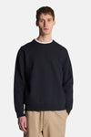 Sweat bleu de LYLE & SCOTT, avec un col rond et des manches longues, porté avec un pantalon beige.