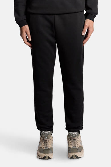 Zwarte joggingbroek van LYLE & SCOTT, effen textiel met een hand op het dijbeen.