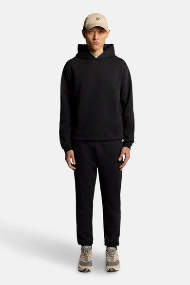 Zwarte joggingbroek van LYLE & SCOTT, gedragen met een zwarte hoodie en neutrale sneakers.