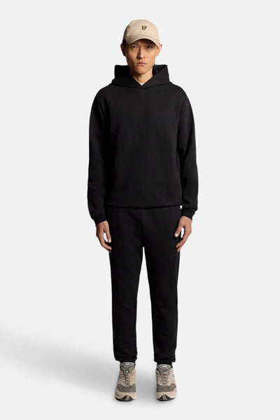 Jogging noir de LYLE & SCOTT, porté avec un sweat à capuche noir et des baskets neutres.