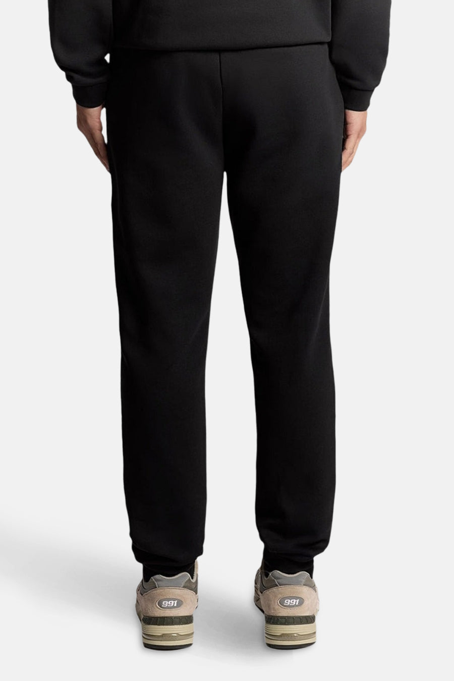 Zwarte joggingbroek van LYLE & SCOTT, gedragen met neutrale sneakers met dikke zolen, achterzijde.