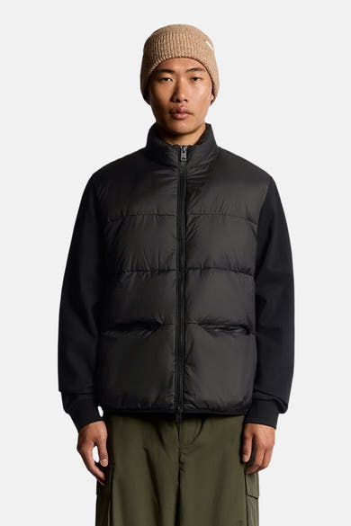 Veste de pluie noire de Lyle & Scott avec manches longues et fermeture éclair sur un homme portant un bonnet.