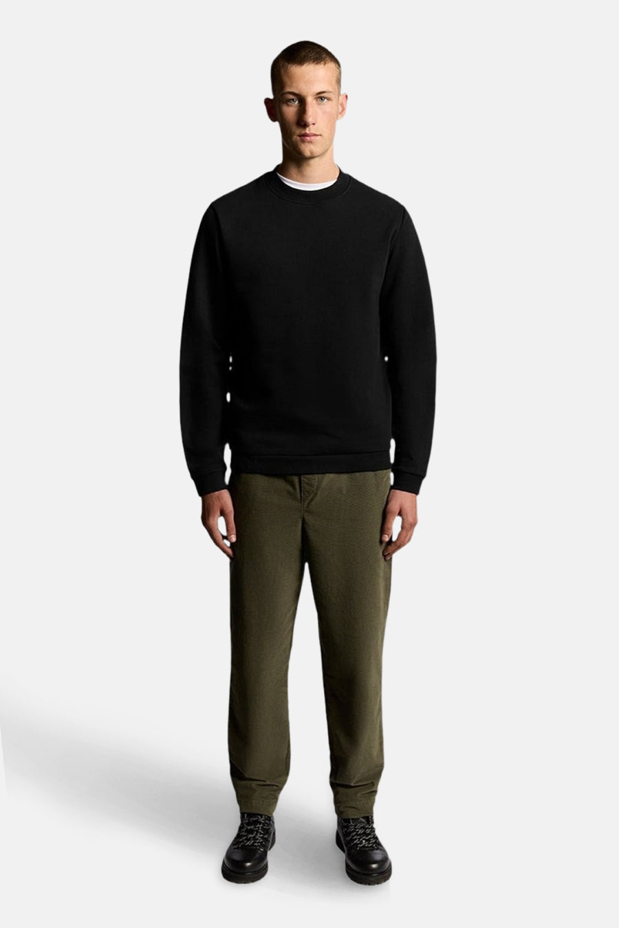 Zwarte trui van LYLE & SCOTT, gedragen met een olijfgroene broek en wandelschoenen.