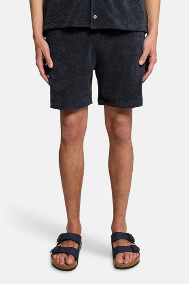 Short bleu de LYLE & SCOTT avec motif texturé et sandales sans marque visibles.
