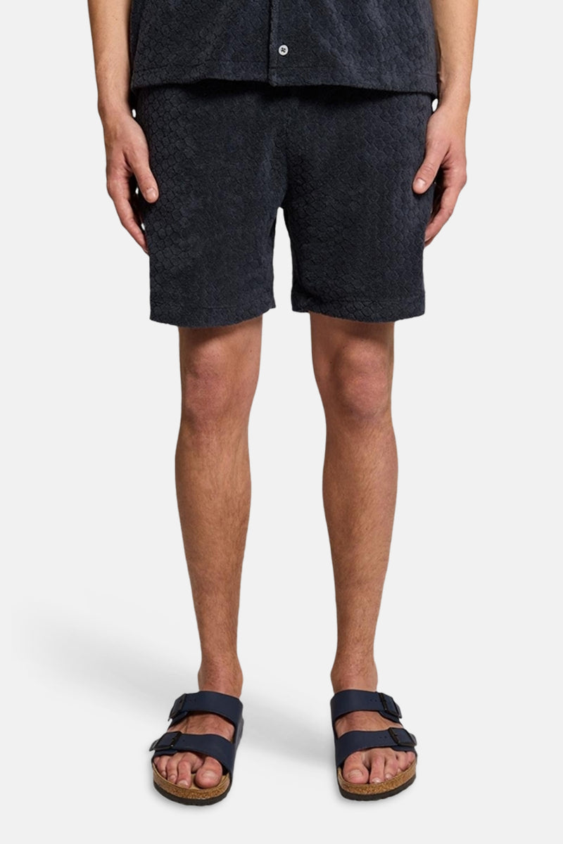 Short bleu de LYLE & SCOTT avec motif texturé et sandales sans marque visibles.
