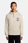 Sweat à capuche écru de LYLE & SCOTT avec un motif floral coloré sur la poitrine et une poche kangourou, porté par un homme.