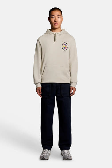 Sweat à capuche écru de LYLE & SCOTT, motif graphique coloré sur la poitrine et poche kangourou, porté par un homme.