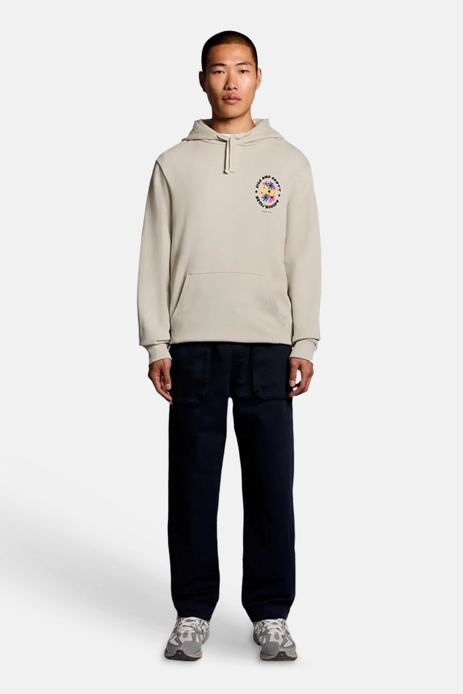 Sweat à capuche écru de LYLE & SCOTT, motif graphique coloré sur la poitrine et poche kangourou, porté par un homme.