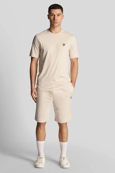 Short beige de LYLE & SCOTT, porté avec un t-shirt coordonné, des chaussettes blanches et des baskets couleur crème.