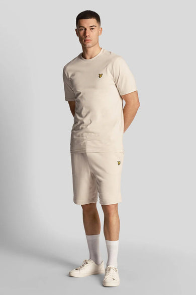 Short beige de LYLE & SCOTT, porté avec un t-shirt assorti, des chaussettes blanches et des chaussures de sport.