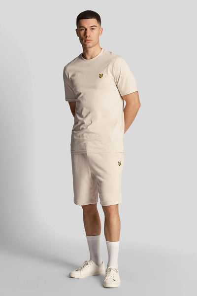 Short beige de LYLE & SCOTT, porté avec un t-shirt assorti, des chaussettes blanches et des chaussures de sport.