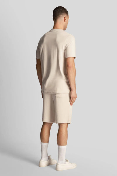 Short beige de LYLE & SCOTT, porté avec un t-shirt et des chaussures assortis, vue de dos.