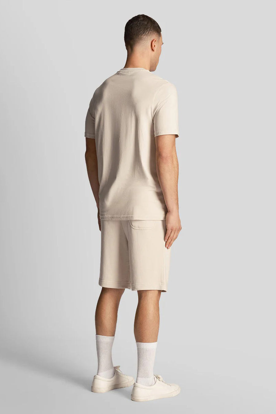 Korte beige short van LYLE & SCOTT, gedragen met een bijpassend T-shirt en schoenen, van achteren gezien.