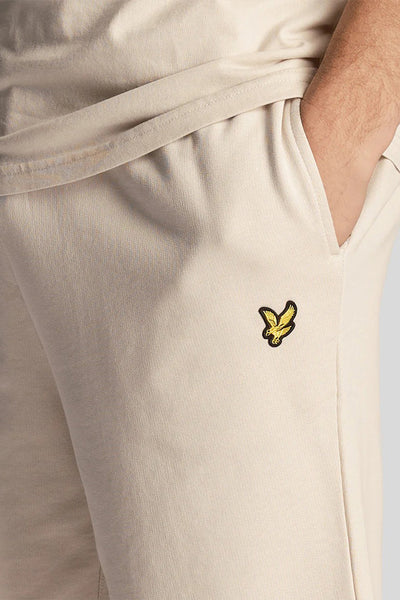 Short beige de LYLE & SCOTT, avec une main dans la poche, arborant le logo brodé.