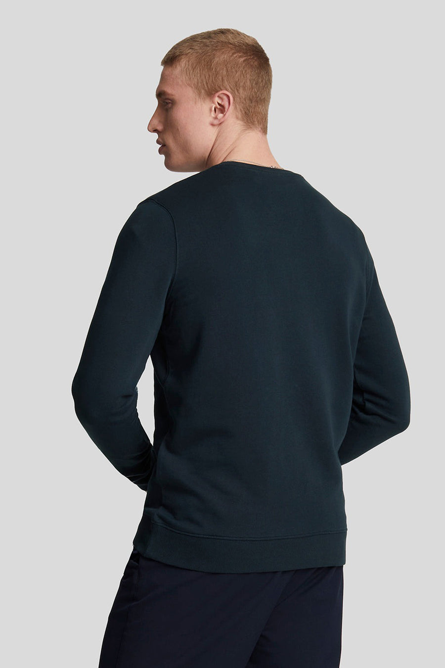 Blauwe sweater van LYLE & SCOTT, achterkant, gedragen met een marineblauwe broek.
