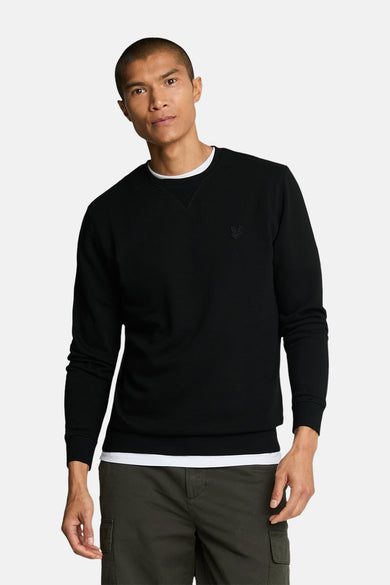 Zwarte trui van LYLE & SCOTT, met ribhaak en klassieke pasvorm, gedragen met een cargo broek.