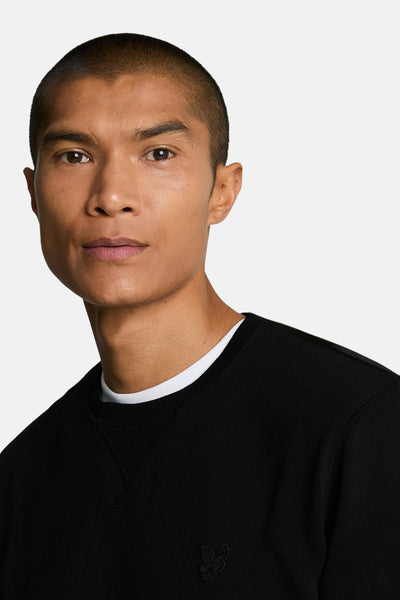 Sweat-shirt noir à col rond de LYLE & SCOTT, avec un logo brodé discret sur la poitrine.