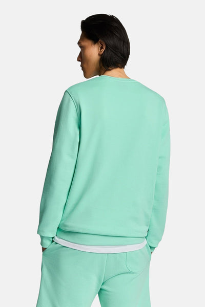 Sweat turquoise de Lyle & Scott, porté avec un t-shirt blanc et un pantalon de survêtement assorti, vue de dos.