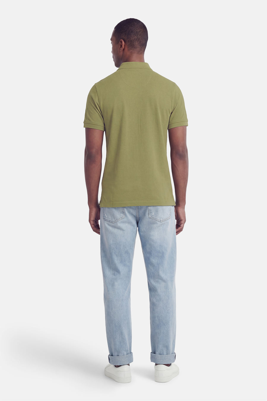 Polo vert à manches courtes de BARBOUR CLASSIC, vu de dos, avec un motif texturé, porté avec un jean clair et des baskets blanches.