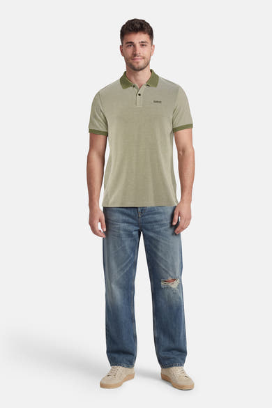 Polo vert à micro-motif de BARBOUR, porté par un homme en jean déchiré et baskets beiges.