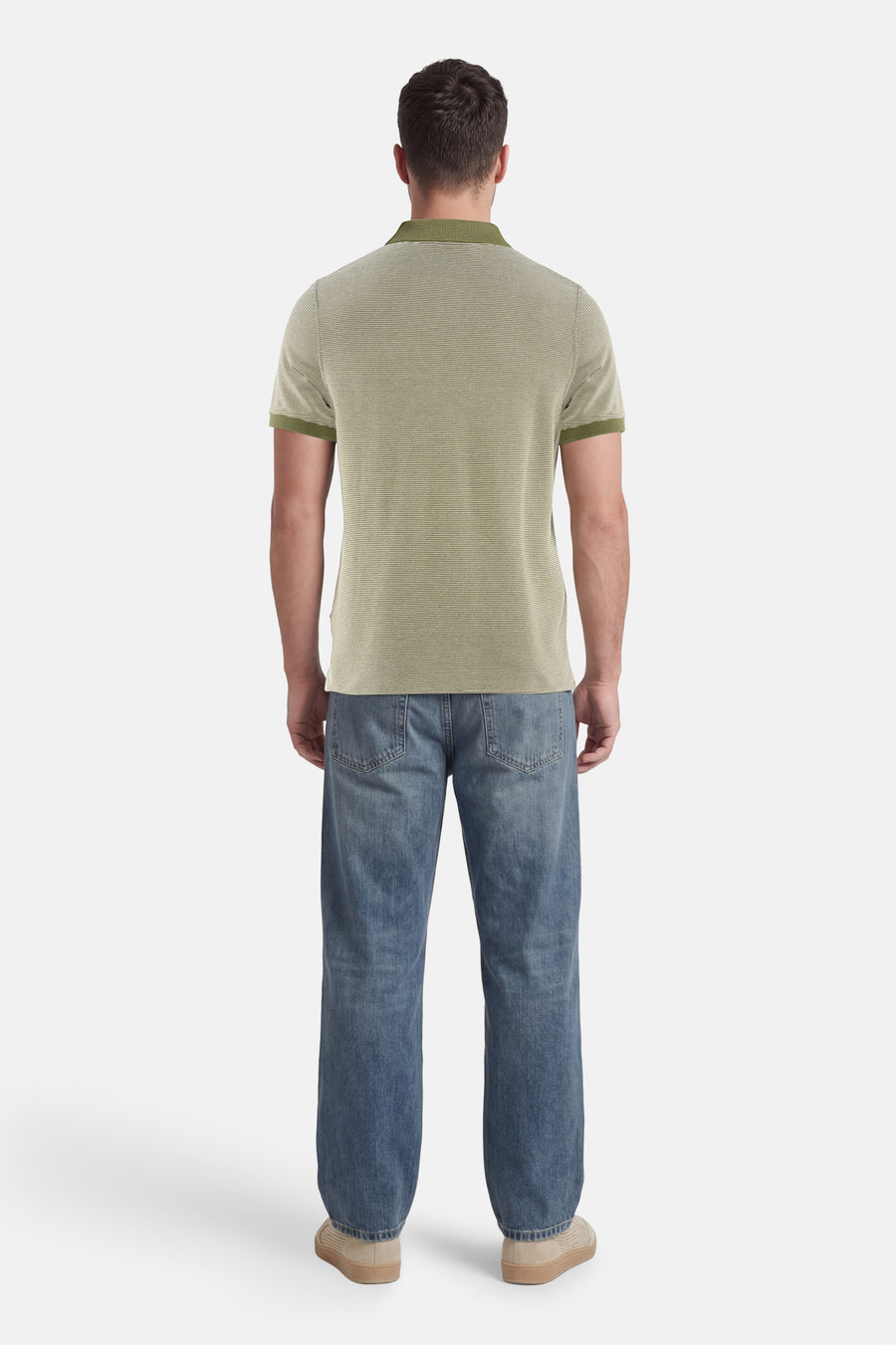 Polo vert de BARBOUR à fines rayures horizontales, col et poignets côtelés vert foncé, porté de dos avec un jean bleu et des chaussures beiges.
