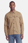 Beige long-sleeve shirt with button-down front and two chest pockets, worn by model with blue jeans, front view