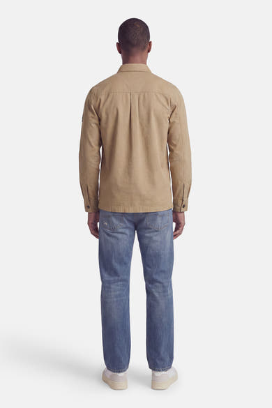 Beige long-sleeve shirt back view with central seam, worn with blue jeans and white sneakers