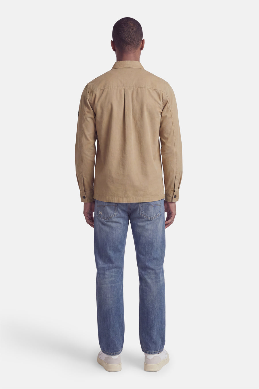 Beige long-sleeve shirt back view with central seam, worn with blue jeans and white sneakers