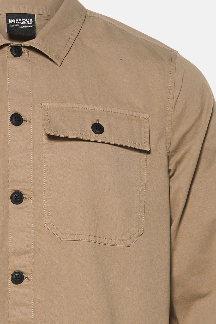Beige long-sleeve shirt by Barbour International with chest pocket, black buttons, and visible stitching, close-up front view