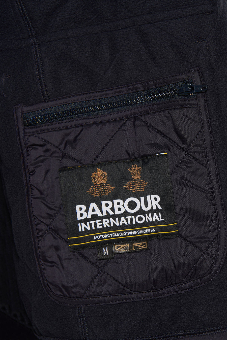 Donkerblauwe Barbour International regenjas met ritszak en gewatteerd patroon.