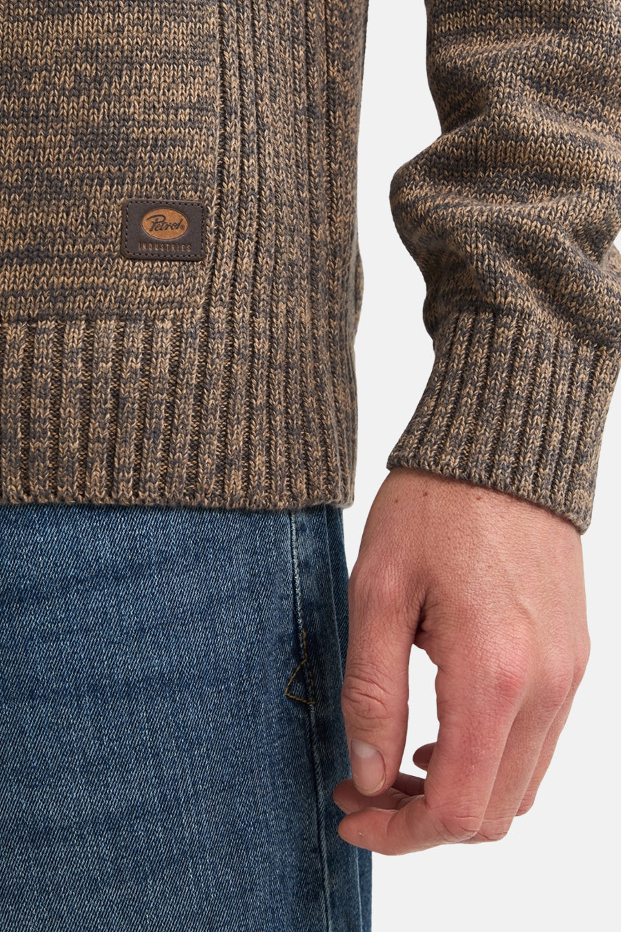Ecru ribbed knit crewneck sweater by Petrol Industries, featuring marled brown texture and leather brand patch, worn with blue jeans, side view close-up