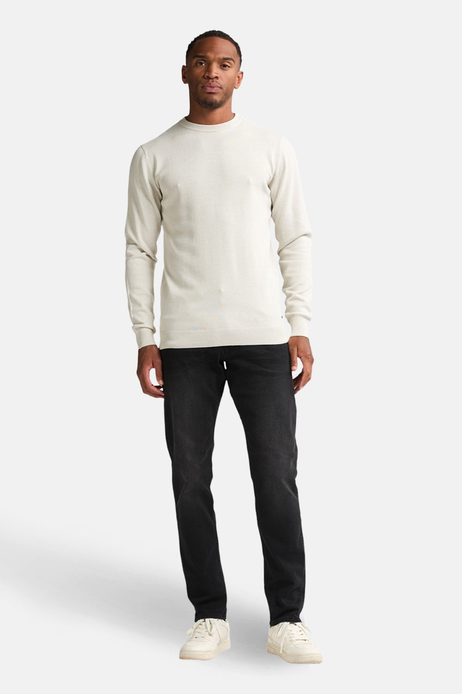 Ecru ronde hals trui van Petrol Industries, gedragen met een zwarte jeans en witte sneakers.