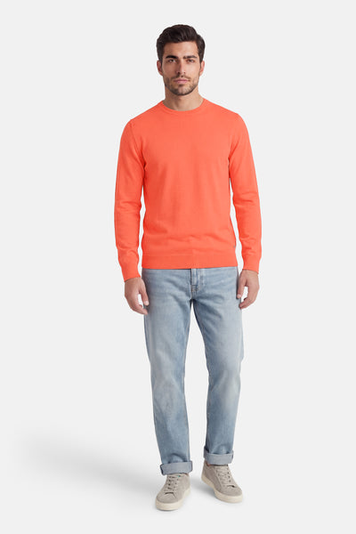 Pull à col rond corail de Petrol Industries®, porté avec un jean délavé retroussé et des baskets grises.
