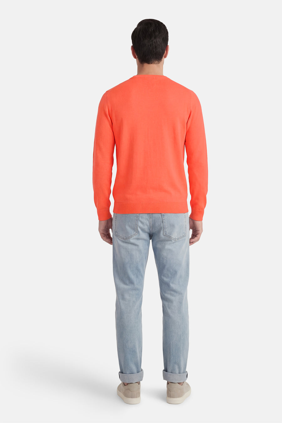 Pull à col rond corail de Petrol Industries®, avec des manches longues, porté avec un jean et des baskets beiges.