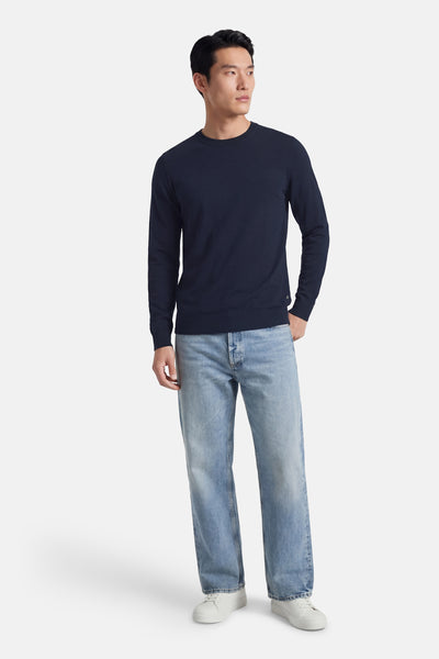 Pull à col rond bleu de Petrol Industries®, porté avec un jean clair et des baskets blanches.