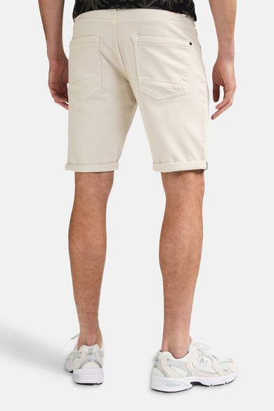 Short écru de Petrol Industries® vue de dos avec revers aux jambes et poches arrière plaquées, porté avec un t-shirt imprimé et des baskets blanches.