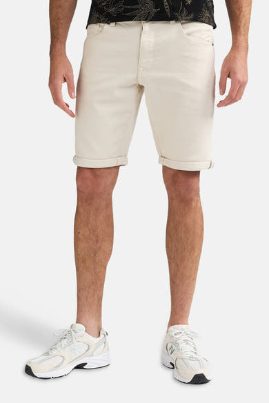 Short écru de Petrol Industries avec revers, porté par un homme avec un t-shirt imprimé foncé et des baskets claires.