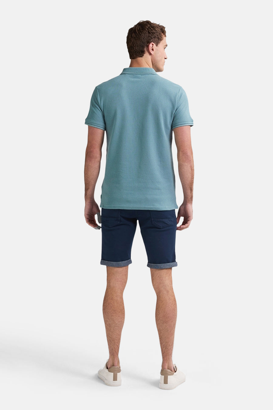 Short bleu foncé de Petrol Industries, avec ourlets retroussés, porté avec un polo bleu clair et des chaussures blanches.