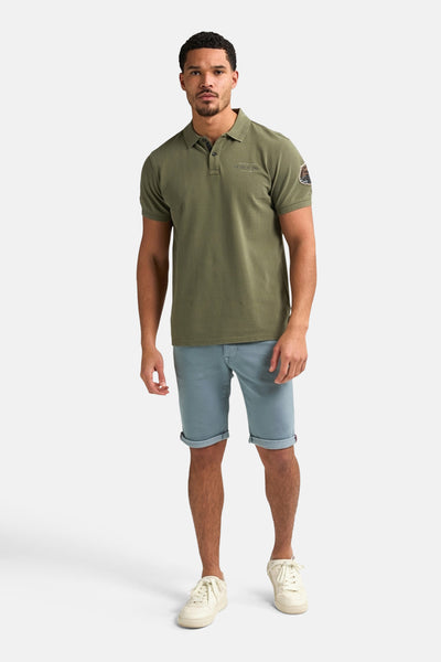 Korte blauwe short van Petrol Industries met rode zoom en olijfgroen T-shirt.