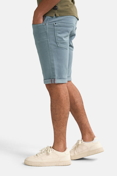 Short bleu de Petrol Industries avec ourlet rouge et t-shirt vert olive.