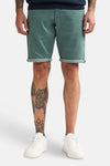 Korte, casual groene short van Petrol Industries met omslag, gedragen door een man met getatoeëerde benen en witte sneakers.