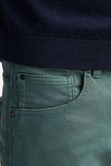 Short vert de Petrol Industries, avec poches à surpiqûres et rivets, porté avec un pull marine.