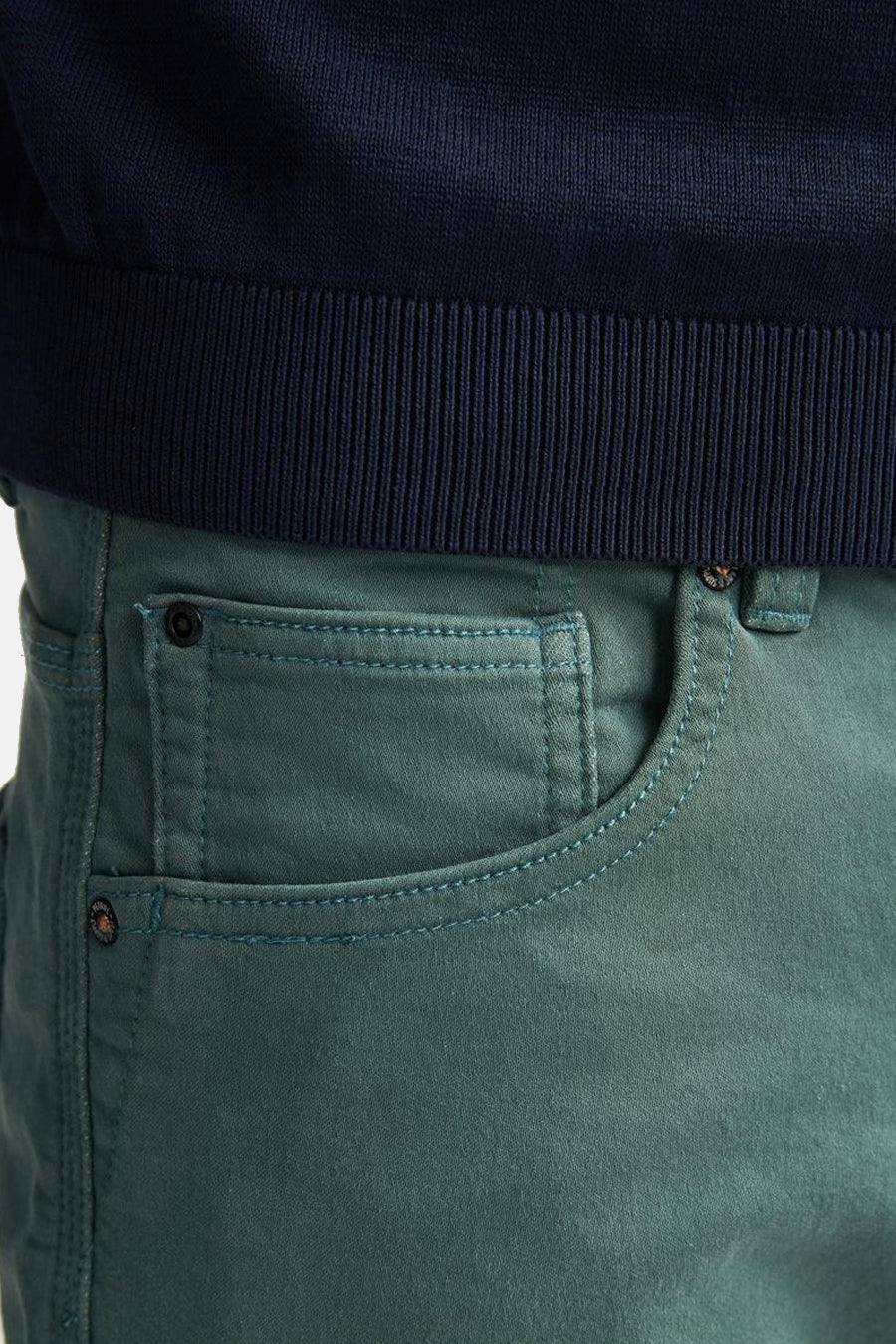 Short vert de Petrol Industries, avec poches à surpiqûres et rivets, porté avec un pull marine.