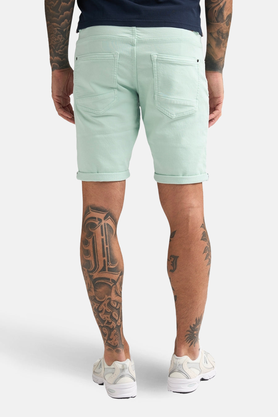 Kort groen Petrol Industries® jack, model met revers, gedragen met een marineblauw T-shirt en witte schoenen.