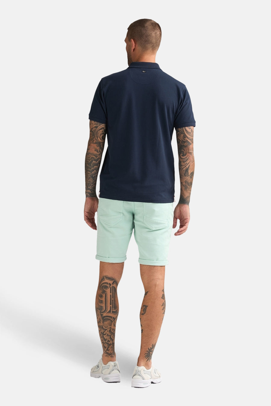 Kort groen Petrol Industries T-shirt, met opgerolde zoom en gedragen met een marineblauw poloshirt.