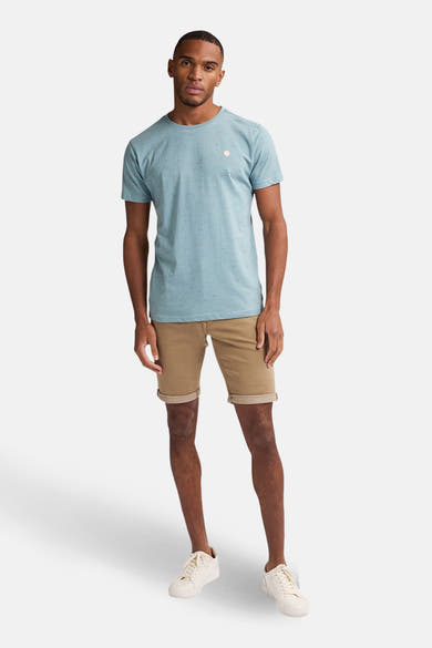 Korte beige short van Petrol Industries, gedragen met een blauw T-shirt en witte sneakers.