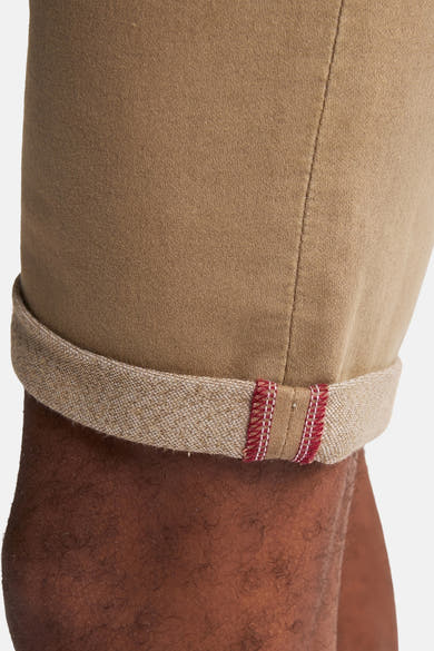 Korte beige short van Petrol Industries met een omgeslagen zoom die een rode bies onthult.