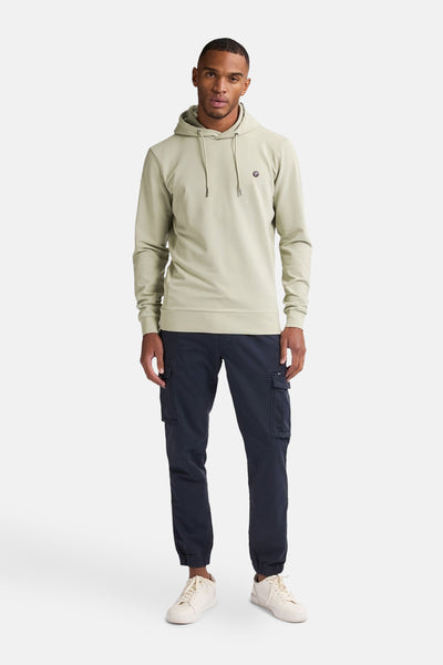 Petrol Industries groene hoodie, gedragen met een marineblauwe cargo broek en witte sneakers.