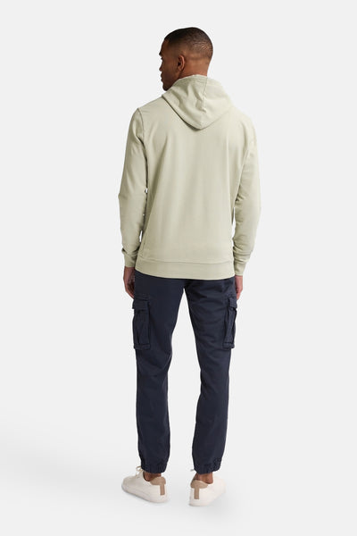 Groene hoodie van Petrol Industries, gezien van achteren, gedragen met een donkergroene cargo broek en beige sneakers.