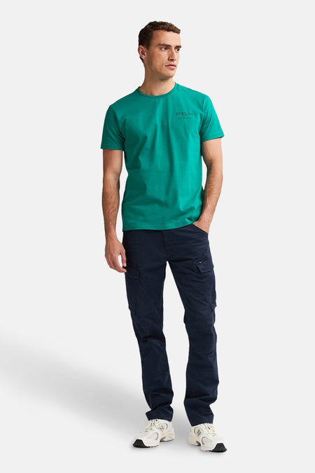 Pantalon cargo bleu foncé de Petrol Industries, porté avec un t-shirt vert et des baskets blanches.